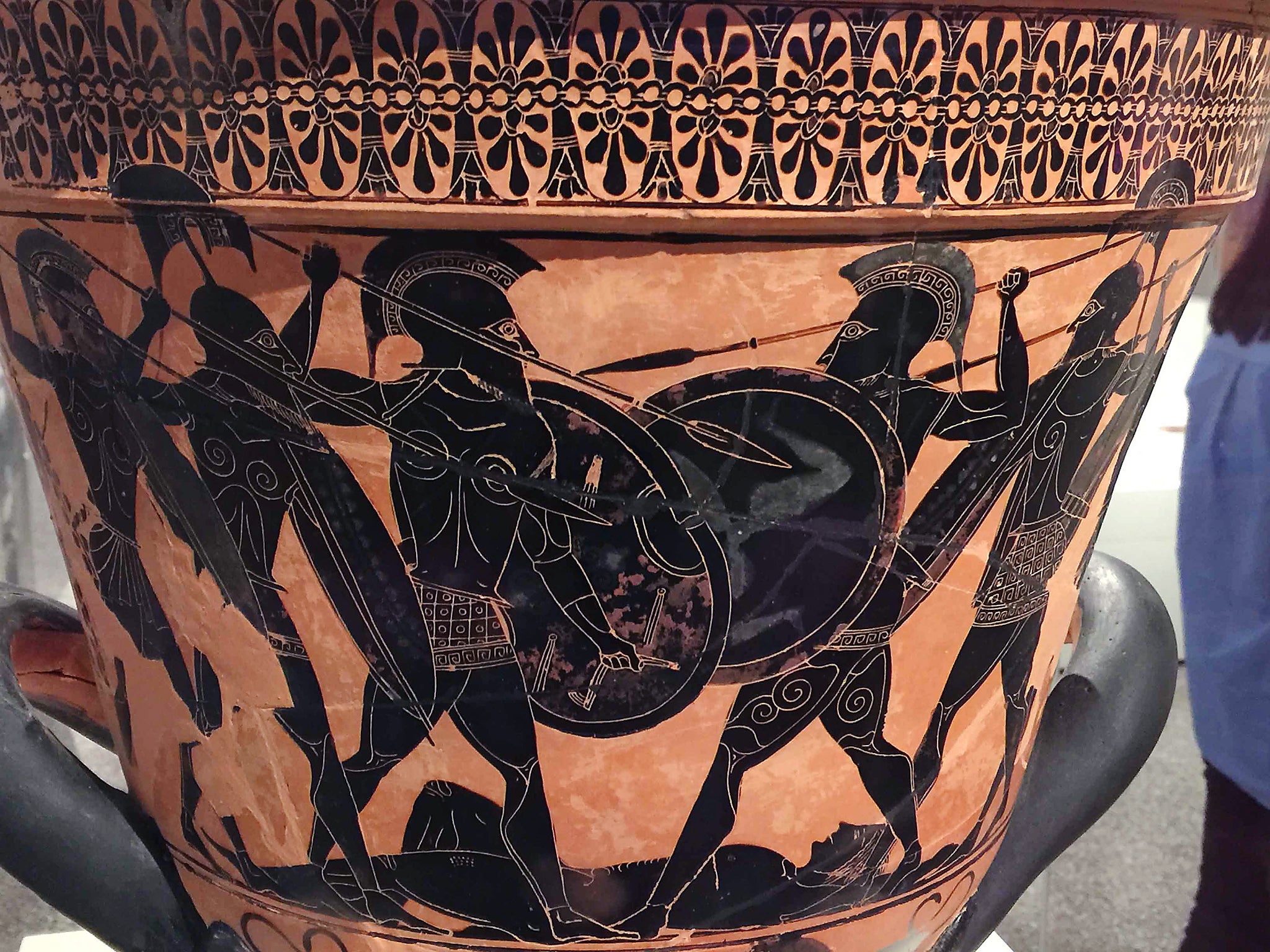 <p>Una escena de una batalla de la Guerra de Troya realizada en técnica de figuras negras. La escena, tomada de la ‘Ilíada’ de Homero, probablemente muestra el combate que se libra alrededor del cadáver de Patroclo, cuya muerte impulsó a Aquiles a reincorporarse a la batalla de manera decisiva</p>