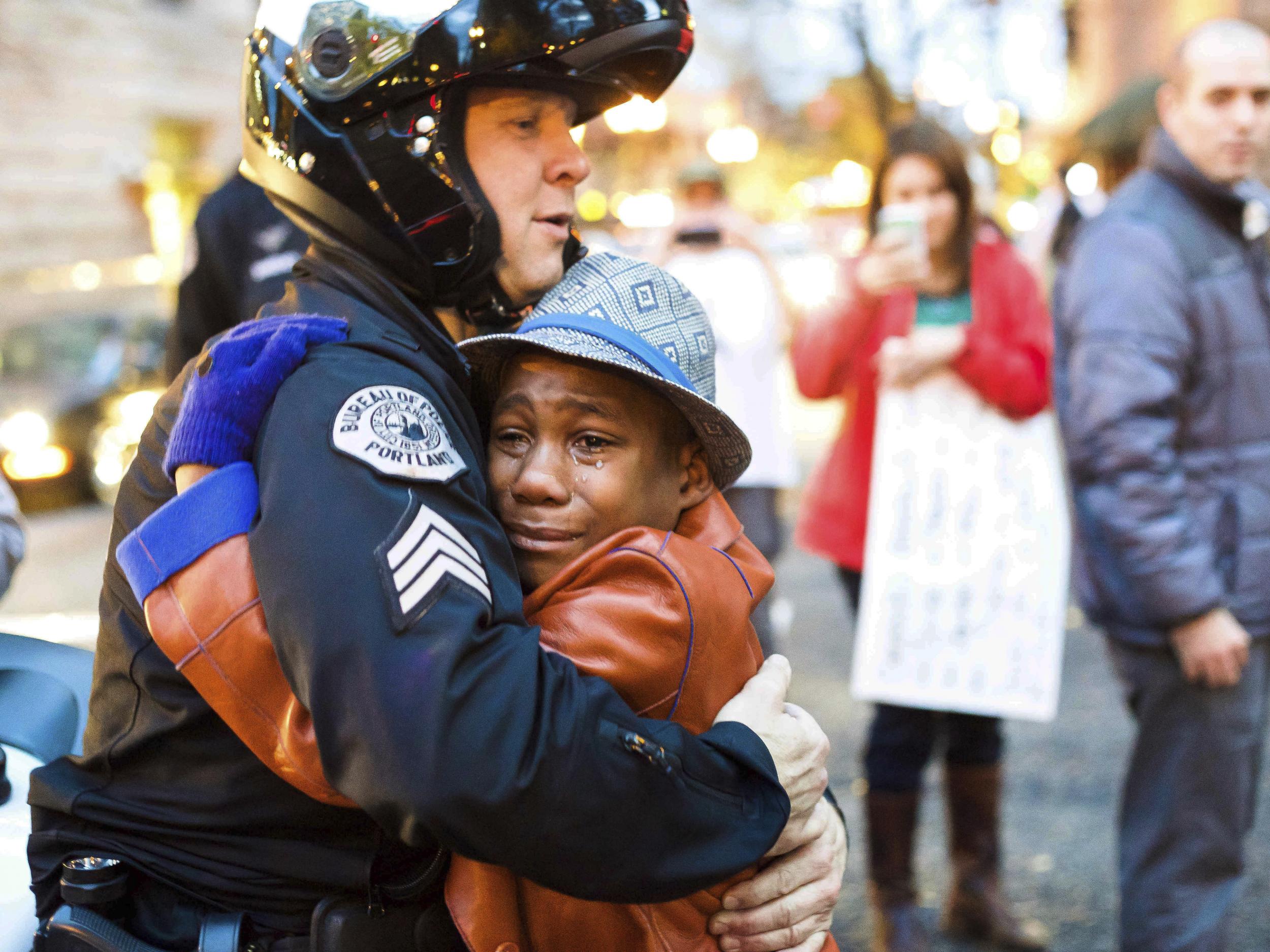 El sargento de policía de Portland, Bret Barnum (izq) y Devonte Hart, de 12 años, se abrazan durante una manifestación en Oregón donde la gente se reunió para apoyar las protestas en Ferguson