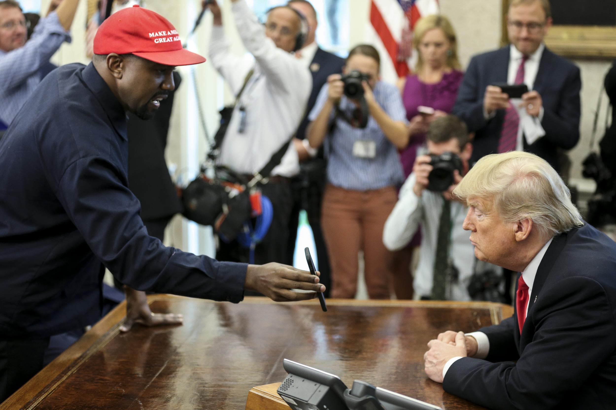 Kanye West shows a picture of a plane to Donald Trump during a meeting in the Oval office of the White House