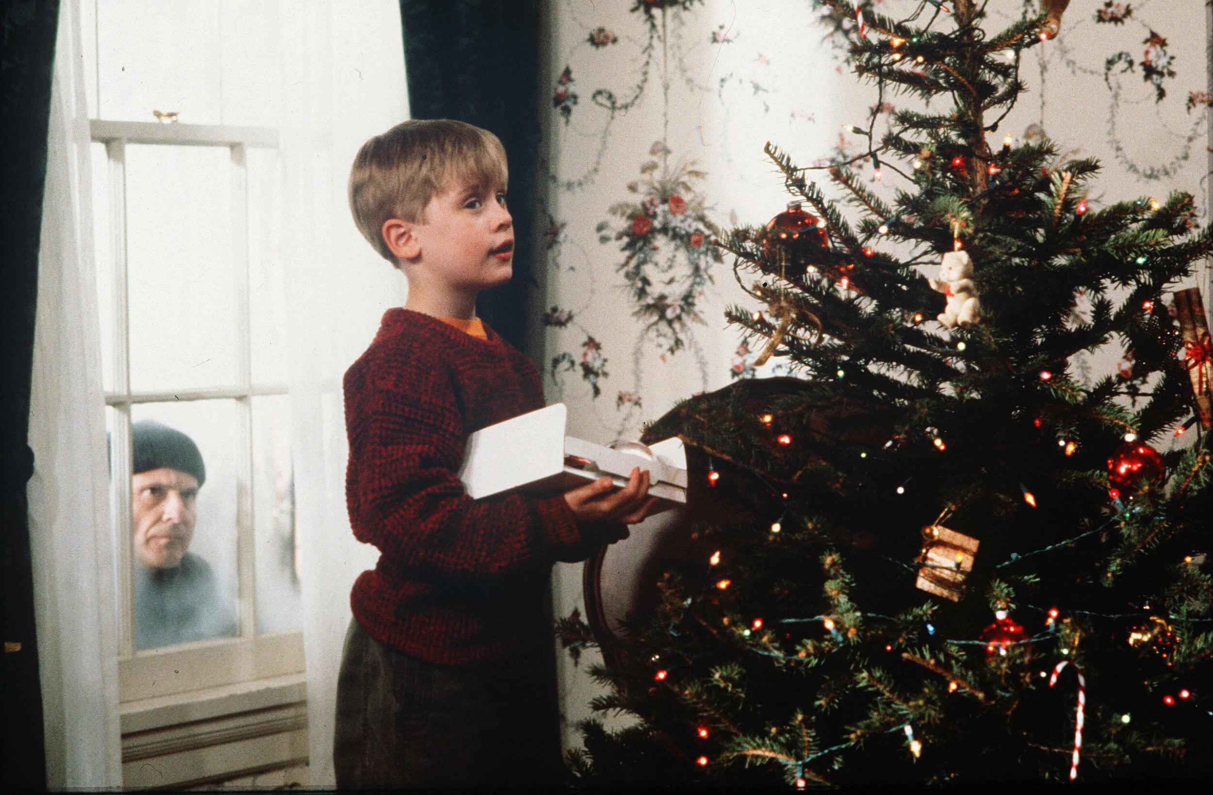 Maucalay Culkin, que interpreta a Kevin McCallister, decora un árbol de Navidad mientras Joe Pesci de ladrón mira hacia el interior de la casa en Winnetka, Illinois, un suburbio al norte de Chicago