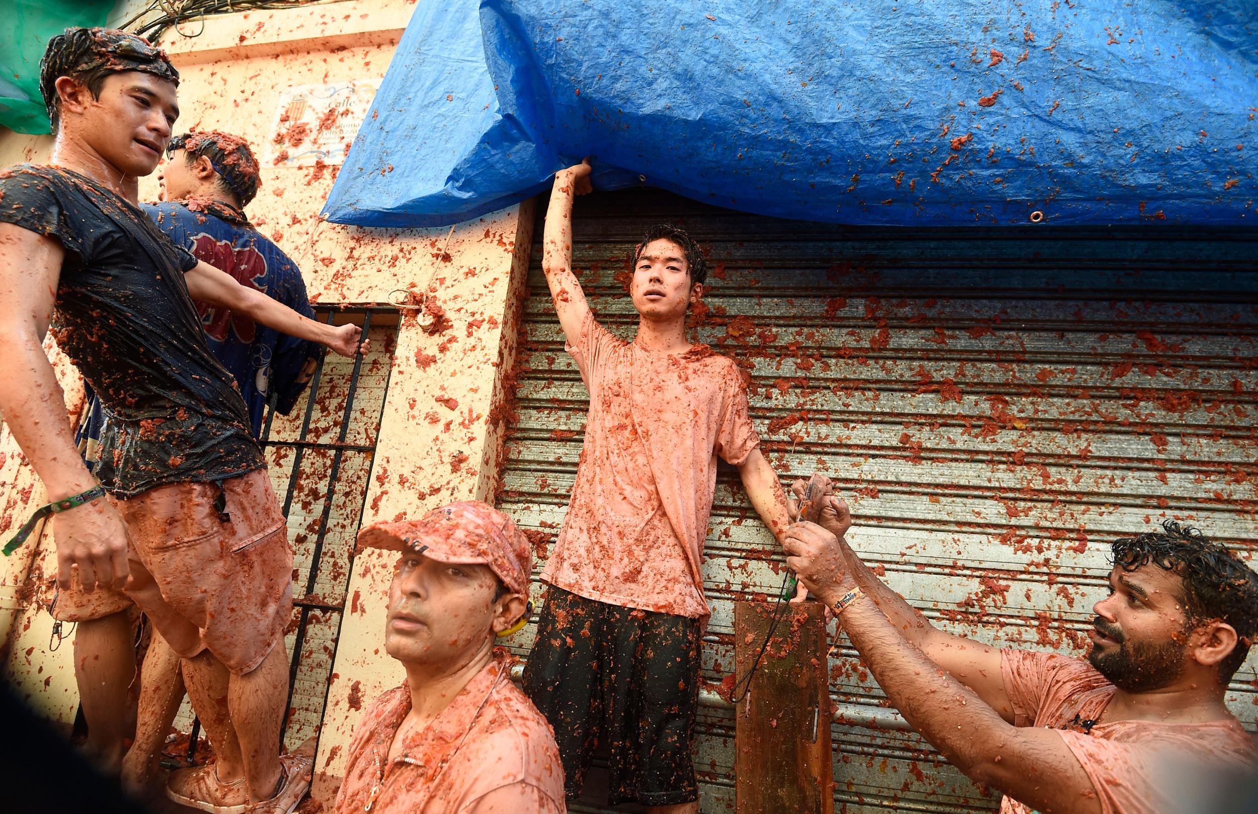 Revellers covered up with smashed tomatoes take part in the 'Tomatina' festival in Bunol