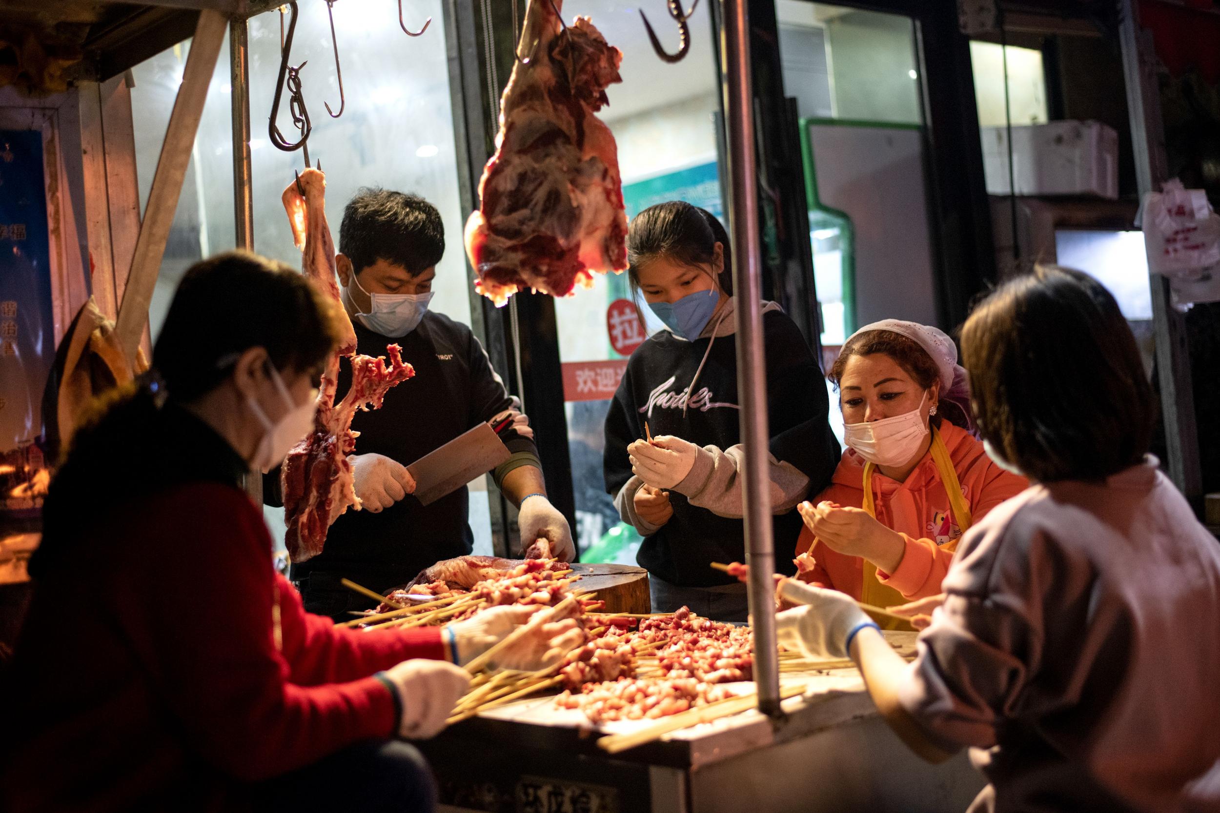 Trabajadores preparan una parrilla en un mercado de Wuhan, China