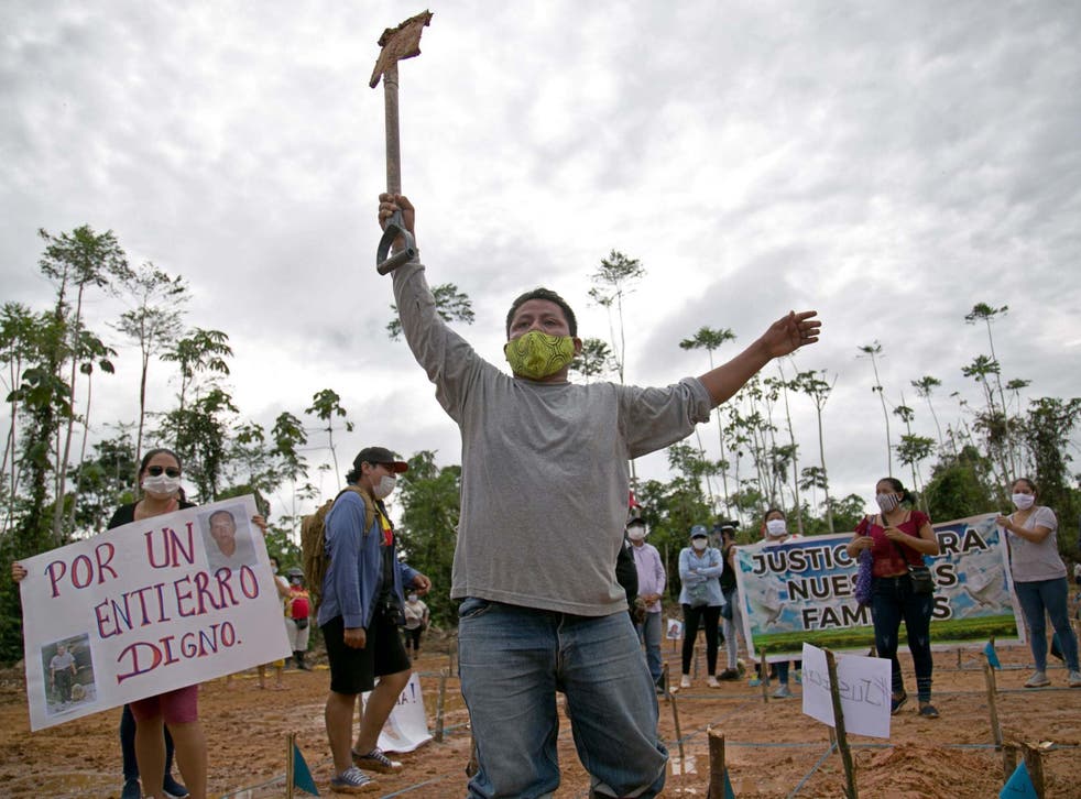 Un familiar de una víctima de COVID-19 sostiene una pala junto a otro familiar quien levanta un cartel que dice "Por un entierro digno".
